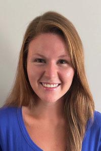 White woman with red hair wearing a blue shirt